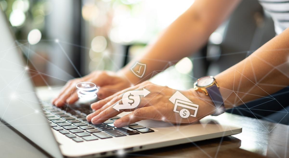 Persona en computador desde donde salen iconos de movimiento de dinero